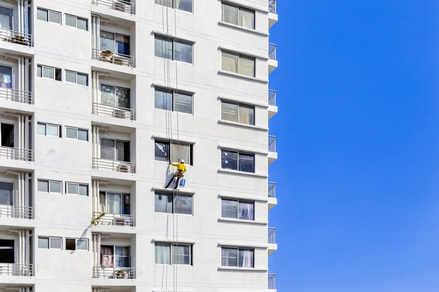 Arbeiter seilen sich außerhalb des Gebäudes ab, um es zu streichen